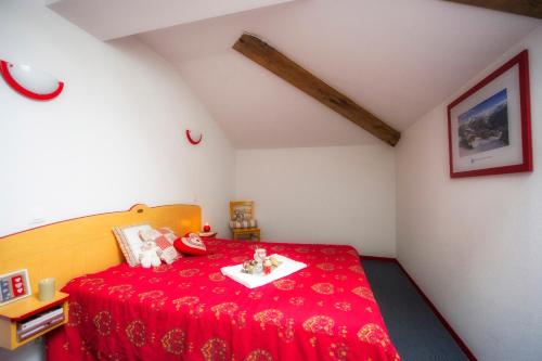 un dormitorio con una cama roja con animales de peluche en Résidence Goélia Les 4 Vallées en Saint-François-Longchamp