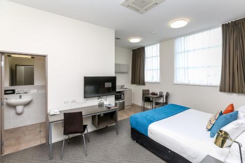 a hotel room with a bed and a desk and a sink at Quest New Plymouth Serviced Apartments in New Plymouth