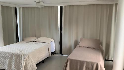 a hotel room with two beds and a window at Casa com churrasqueira e Wi-Fi na Praia de Camburí in São Sebastião