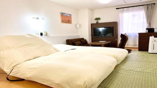 a hotel room with two beds and a flat screen tv at Business Hotel Raicho in Koshigaya