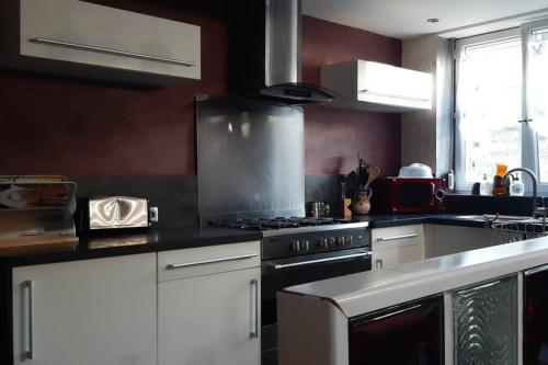 une cuisine avec des armoires blanches et un four à plaques de cuisson dans l'établissement La Cour Pavée, à Boulogne-sur-Mer