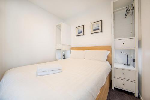 a small bedroom with a white bed and white cabinets at Snow Ski Apartments 20 in Falls Creek