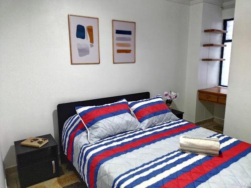 een slaapkamer met een bed met een kleurrijk gestreepte deken bij Laureles 301 in Medellín