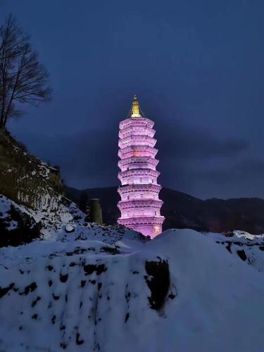 a lit up pagoda in the snow at night at ManBuYunDuan.Theme Inn in Wutai