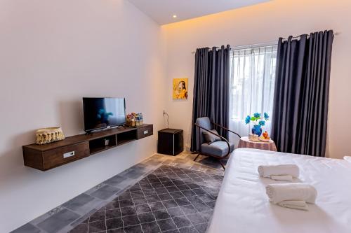 a bedroom with a bed and a tv and a chair at The Dreamers Homestay in Hue