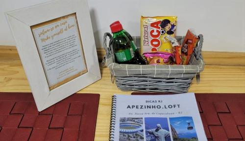 einen Korb mit Snacks, ein Bild und ein Buch in der Unterkunft Apezinho.Loft in Rio de Janeiro