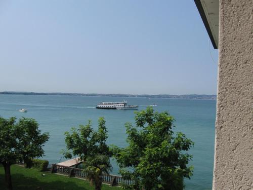 a large boat in the water with a building at Hotel Giardino in Sirmione
