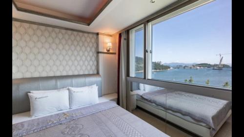 a bedroom with a bed and a large window at Yeosu Beach Hotel in Yeosu