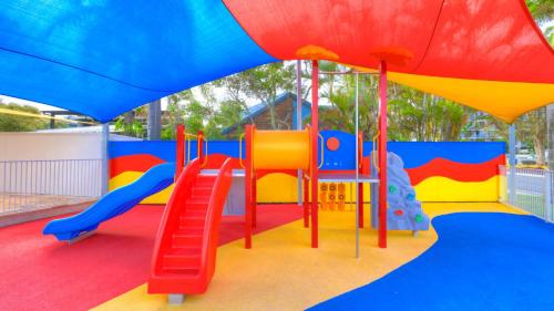 a colorful playground with a slide and a slideintend at Alex Beach Cabins and Tourist Park in Alexandra Headland