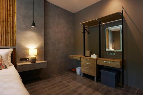 a bedroom with a bed and a dresser and a mirror at Sand Dollar Boutique Hotel in Bang Sare