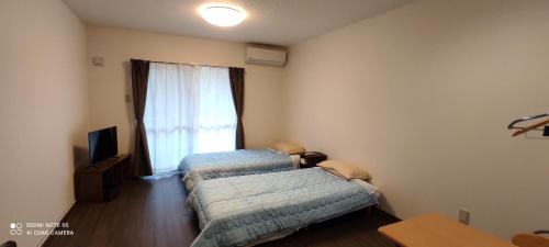 two beds in a room with a window at 明石　美ら馬ハウス in Ishigaki Island