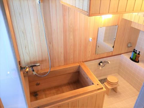 a bathroom with a wooden bath tub with a toilet at IBARA DENIM HOTELS 舞鶴楼 in Ibara
