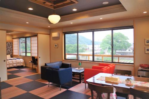 a living room with a table and chairs and windows at IBARA DENIM HOTELS 舞鶴楼 in Ibara