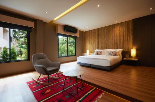 a bedroom with a bed and a chair and windows at Sand Dollar Boutique Hotel in Bang Sare