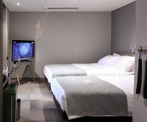 a hotel room with two beds and a flat screen tv at Hotel U5 in Seoul