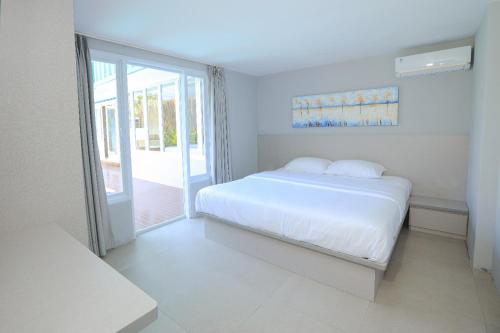 um quarto branco com uma cama e uma porta de vidro deslizante em Lacrissa Bali em Kerobokan