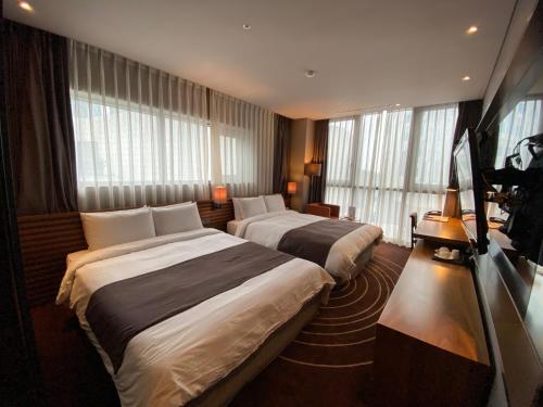 two beds in a hotel room with windows at Best Louis Hamilton Hotel Haeundae in Busan