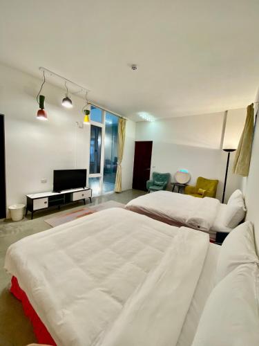 a bedroom with a large white bed and a television at Songyue Homestay in Yilan City