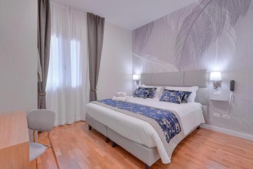 a white bedroom with a large bed with blue sheets at Hotel Cosmos in Florence