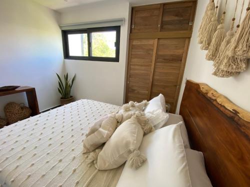 a bedroom with a bed with white pillows and a window at Casa Kuaan Mani TH 1 in Tulum