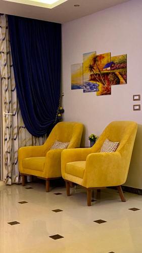 two yellow chairs in a room with a blue curtain at Royal Luxury Apartment with Gorgeous Sea View in Alexandria