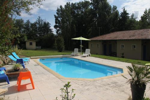 une piscine avec deux chaises et un parasol dans l'établissement Au Petit Bernerot - Les gîtes de l'Arbre Voyageur, à Eauze