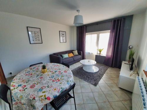 a living room with a table and a couch at Idéalement situé, spacieux et agréable, parking gratuit et classé 3 étoiles in Mende