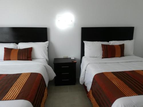a hotel room with two beds and a night stand at Hotel Osalle Inn in Chignahuapan