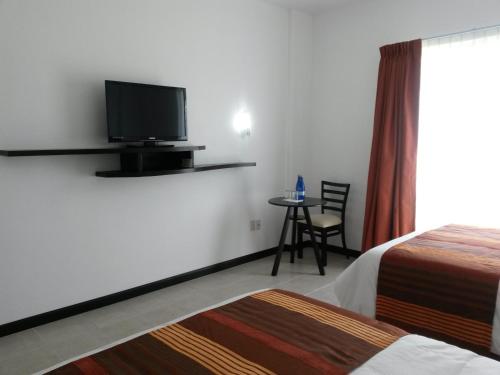 a hotel room with a tv and a bed and a table at Hotel Osalle Inn in Chignahuapan