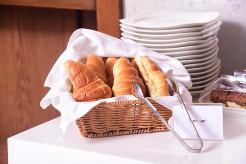 a basket of pastries on a table with plates at Best Western Premier Hotel Gulberg Lahore in Lahore