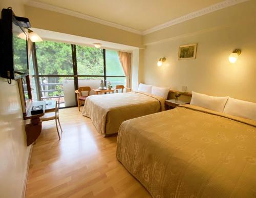 una camera d'albergo con due letti e una televisione di 登山別館 a Zhongzheng