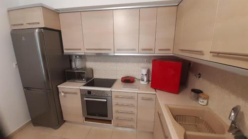a small kitchen with white cabinets and a refrigerator at Villa Maria Louiza NEAR AIRPORT in Artemida