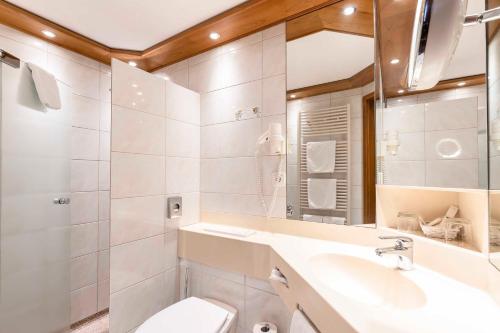 a bathroom with a sink and a toilet and a mirror at Hotel Restaurant Waldsägmühle in Pfalzgrafenweiler