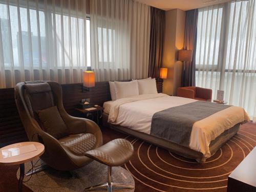a hotel room with a bed and a chair at Best Louis Hamilton Hotel Haeundae in Busan