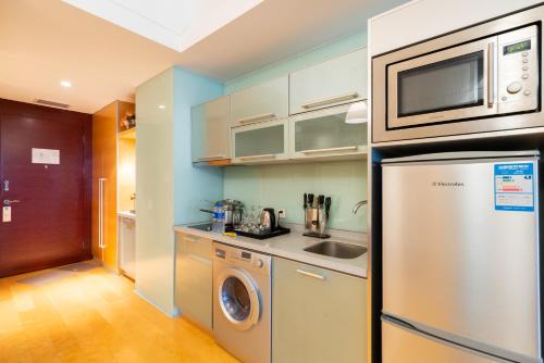 a kitchen with a stainless steel refrigerator and a microwave at Tianjin Crown International Apartment in Tianjin