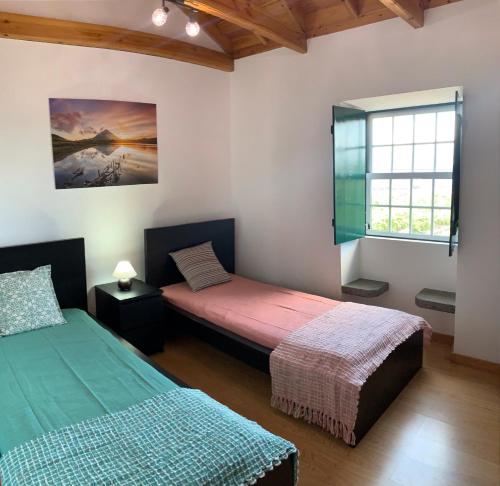 a bedroom with two beds and a window in it at Adega da Prainha in Prainha de Baixo