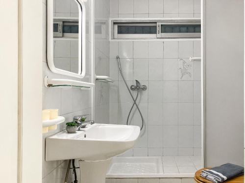 uma casa de banho branca com um lavatório e um chuveiro em Sanny's Place em Kavala