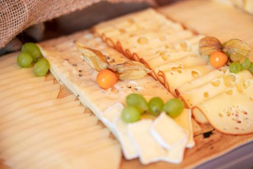 a cake with cheese and grapes on top of it at Manufaktur Boutique Hotel in Stadt Wehlen