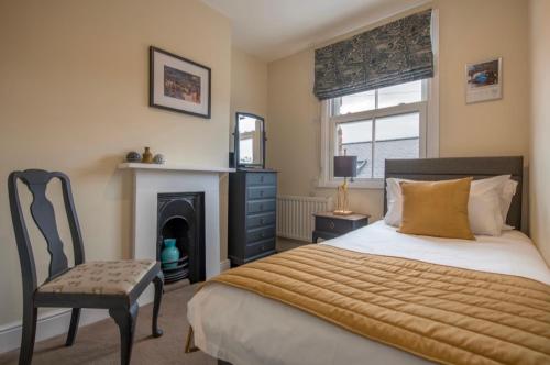 een slaapkamer met een bed en een stoel en een open haard bij 109 Nunnery Lane - a House of York holiday home in York