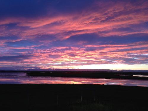 a sunset over a body of water with the sky at Kría Cottages in Skeljabrekka