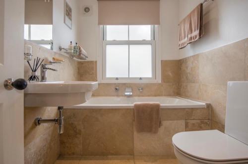a bathroom with a tub and a sink and a toilet at 109 Nunnery Lane - a House of York holiday home in York