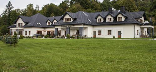 una casa grande con un césped verde delante de ella en Gospoda Magurska, en Sękowa