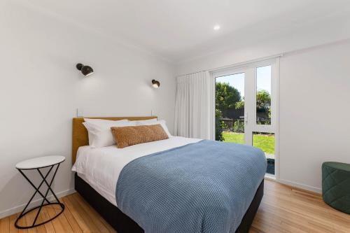 a white bedroom with a bed and a window at Above Par Golf Course Villa with Hot Tub 4bd3bth in Rotorua