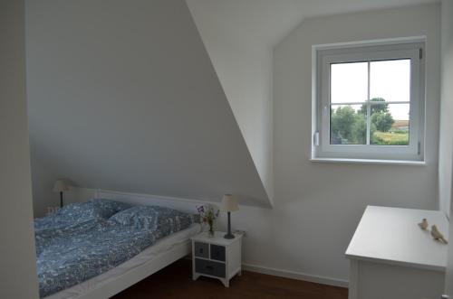 a white bedroom with a bed and a window at Ferienhaus Mück in Ankershagen