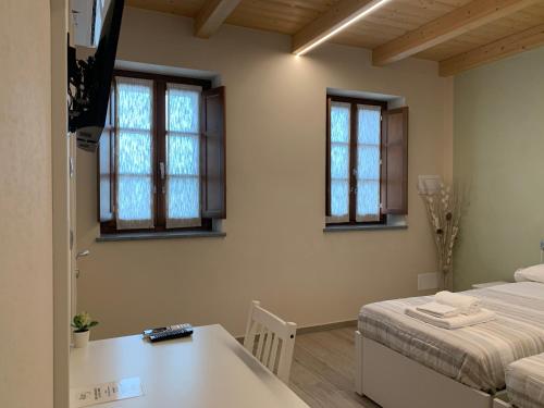 a room with two beds and a table and windows at B&B La Luce Verde in Saluzzo