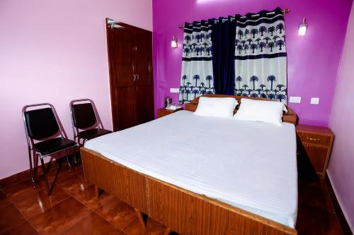 Hotel Virasat Retreat في باتنا: غرفة نوم بسرير كبير مع كرسيين