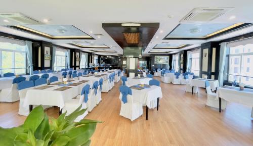 Sea Pearl Cat Ba Hotel في كات با: غرفة طعام مع طاولات بيضاء وكراسي زرقاء