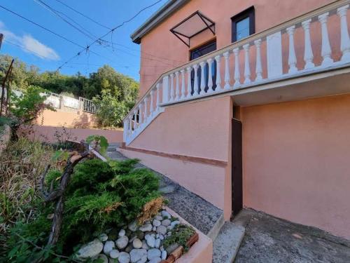 a pink building with a staircase next to a yard at Дом для семейного отдыха в Утехе, Черногория in Utjeha