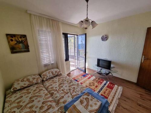 a bedroom with a bed and a flat screen tv at Дом для семейного отдыха в Утехе, Черногория in Utjeha
