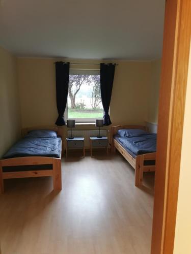 two beds in a room with a window at Hornbrooker Hostel in Dersau